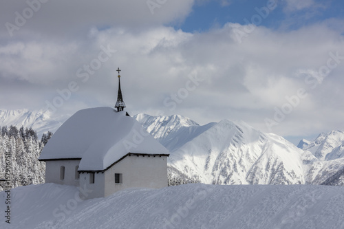 The alpine church immersed in snow frames the high peaks Bettmeralp district of Raron canton of Valais Switzerland Europe