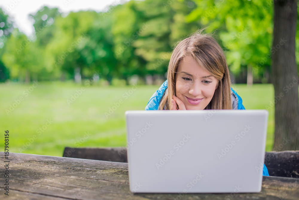 Pretty woman using laptop in park on a sunny day Pretty woman using laptop in park on a sunny day