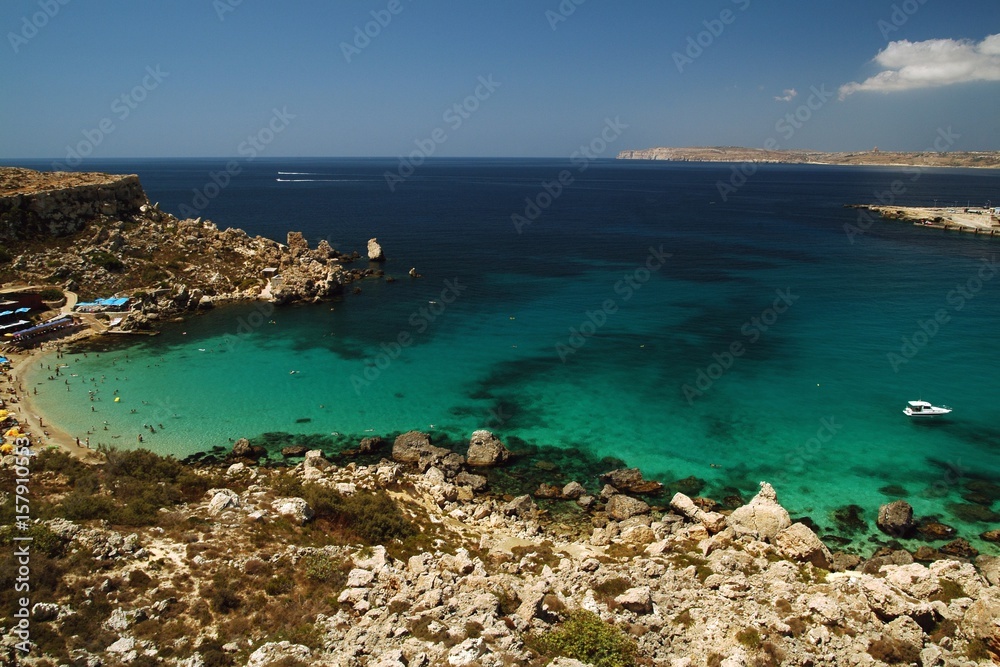 Paradise Bay, a secluded inlet with both a sandy and rocky stretch, surrounding cliffs, crystal clear Mediterranean waters, views of Gozo and the open sea. Malta Europe