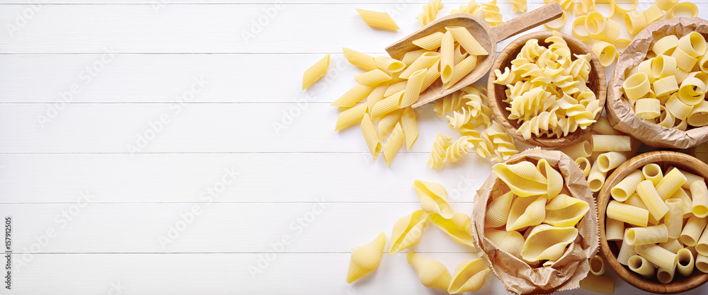 Pasta: pens, shells, rigatoni, fusilli and squid on white wooden background, top view, flat lay, copy space. - obrazy, fototapety, plakaty 