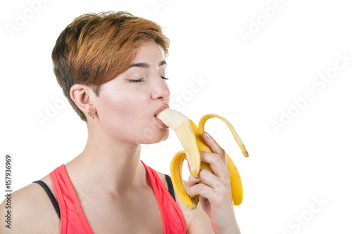 Healthy lifestyle, healthy eating. Young girl passionately and sexually eats a banana, on a white isolated background. Horizontal frame