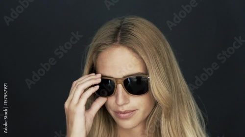 Young woman taking off sunglasses and winking playfully at camera photo