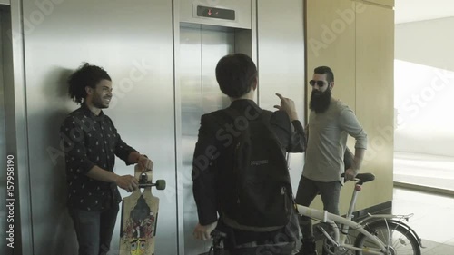 Men waiting by elevator with bikes and skateboard