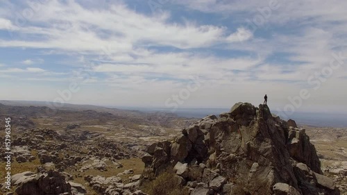 Hiker standing on top of jagged rock formation, Mount Champaqui, Cordoba Province, Argentina photo