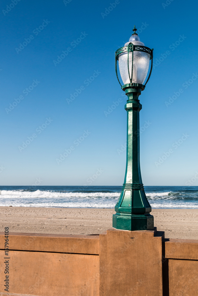 Mission Beach boardwalk lamppost in San Diego, California with beach in the background.