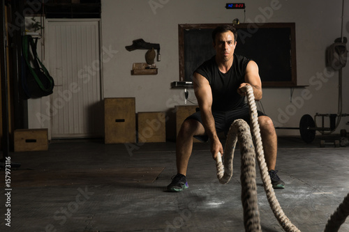 Strong man exercising with battle ropes