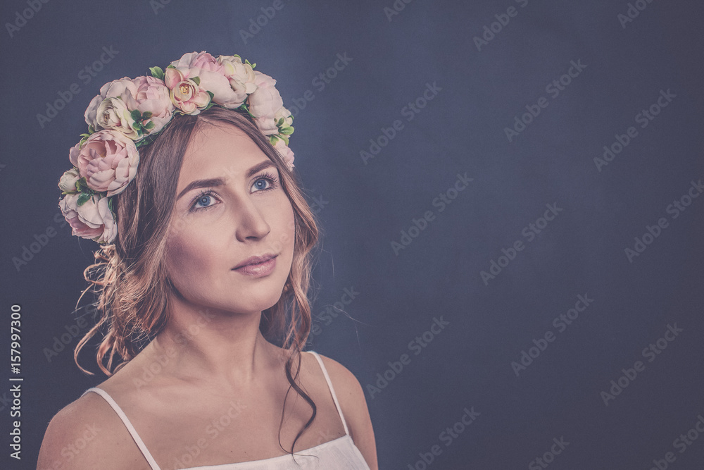 Beautiful girl with flowers on her head on a black background