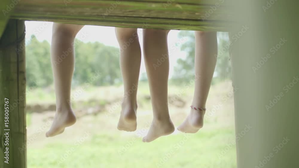 Brother and sister sitting side by side with feet dangling