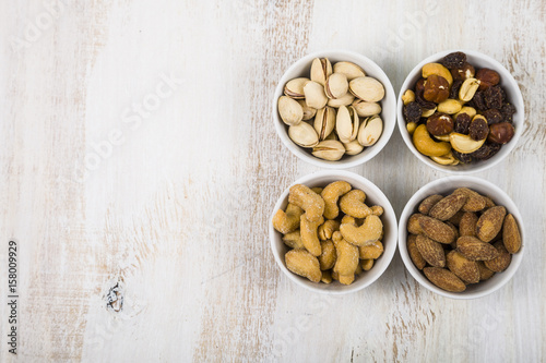 Four bowls with nuts on a  wooden table. © Elena Blokhina