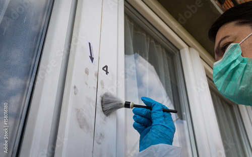Forensic experts finds fingerprints on the window with the help of magnetic brush and black magnetic powder