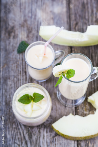 Yogurt and smoothie with melon on a wooden table.
