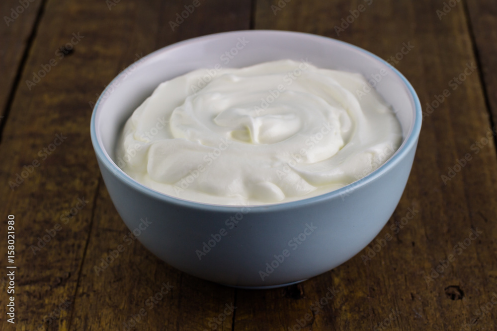 Bowl of natural Greek yoghurt isolated on wooden rustic background Bowl of natural Greek yoghurt isolated on wooden rustic background