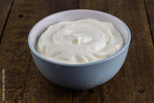 Bowl of natural Greek yoghurt isolated on wooden rustic background