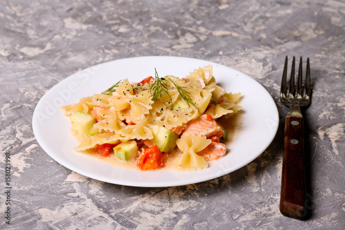 Pasta farfalle with salmon, zucchini and tomate