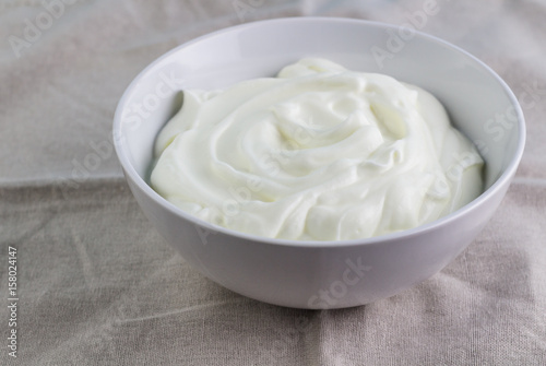 Natural creamy swirled yoghurt in bowl close up - Background with Greek yogurt and space for text