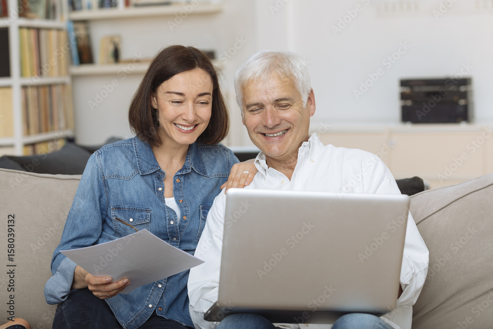 couple using their laptop to pay their bills at home in the living room couple using their laptop to pay their bills at home in the living room