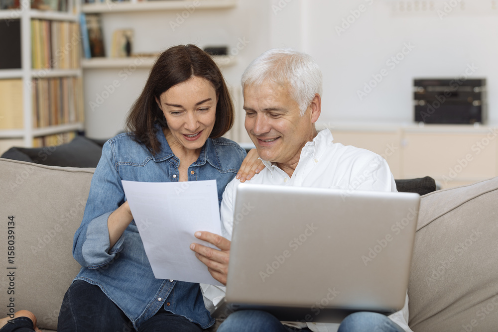 couple using their laptop to pay their bills at home in the living room couple using their laptop to pay their bills at home in the living room
