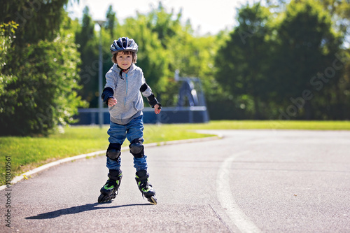 Cute little child, boy, riding on a skating in the park
