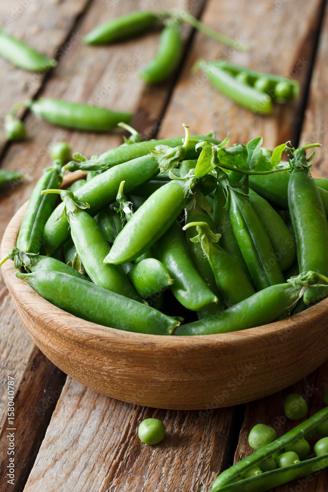 Fresh green peas in a bowl on a wooden background Fresh green peas in a bowl on a wooden background
