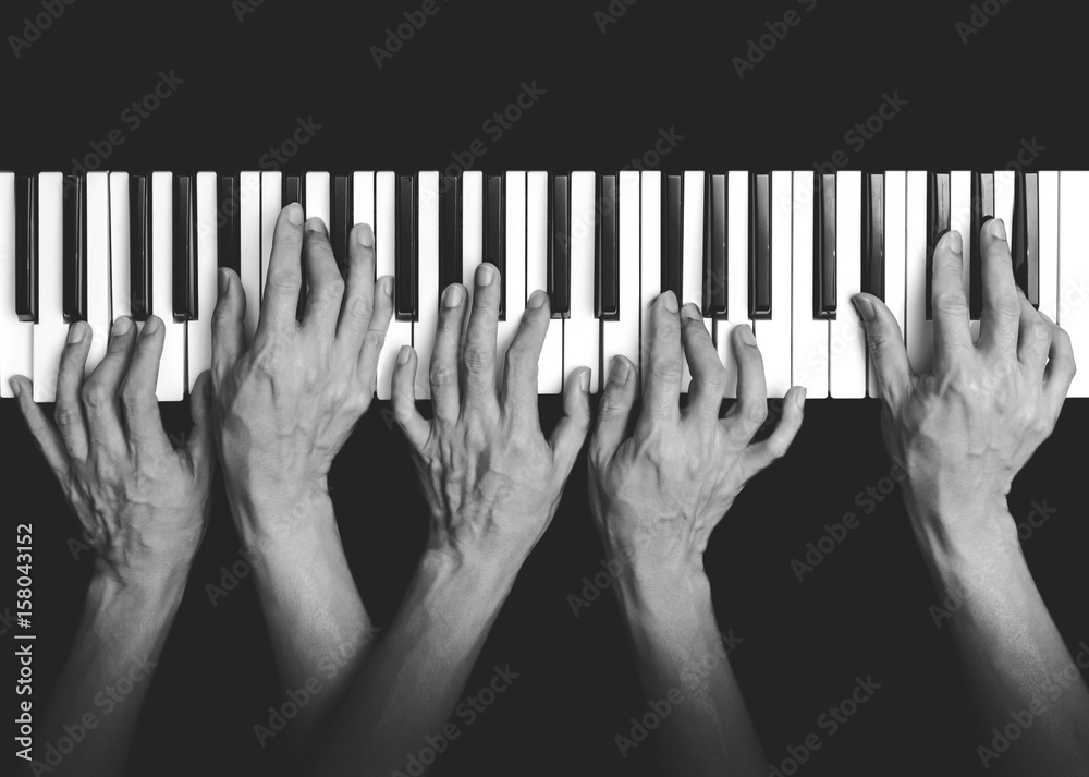 five hands playing on piano keys, black and white. music background