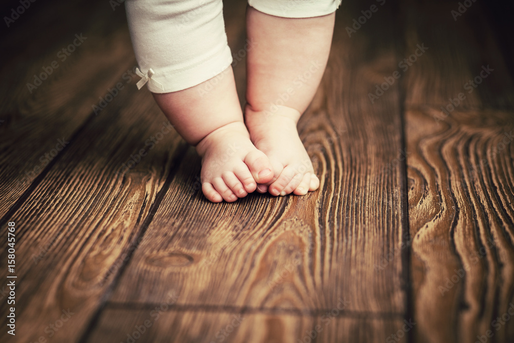 Baby feet doing the first steps. Baby's first steps. Baby feet . - obrazy, fototapety, plakaty 