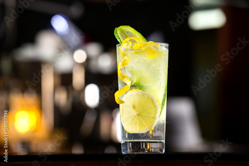 Obraz na plátne Glass of gin tonic cocktail decorated with cucumber at bat counter background