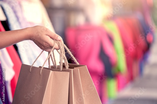 Woman hand holding shopping bags on the street in the shopping mall in vintage color tone