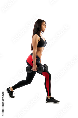 Slender athletic woman shows an exercise of a dumbbell in the hands of a dumbbell, a right foot in front, a position of a semi-squat, on a white background.