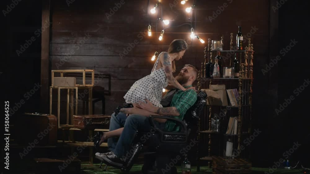 Erotic girl is going to shave her beard to a brutal man who sits on a hairdresser's armchair in a vintage location in Slow motion. Sexy girl with a dangerous razor in her hands boldly kisses a client