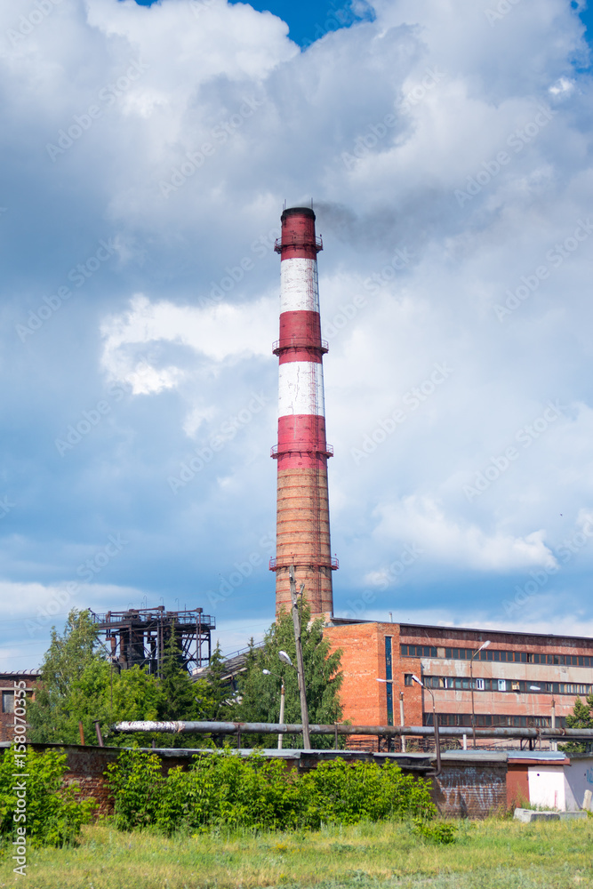 old factory chimney over cloudy sky background