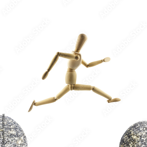 Wooden mannequin is jumping over the abyss isolated on white background. Challenge concept
