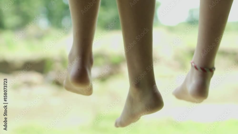 Brother and sister sitting side by side with feet dangling