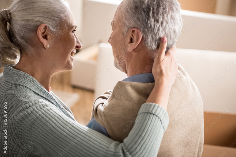 side view of smiling senior woman looking at husband at home