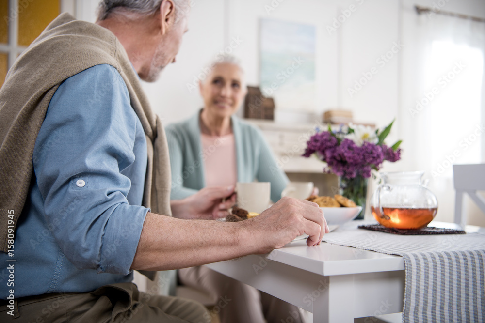 Obraz premium smiling grey haired couple having breakfast at home