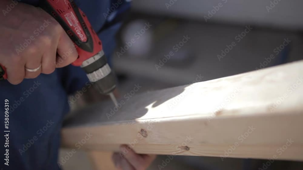 Man using a steel drill and usual screwdriver on wooden plate Man using a steel drill and usual screwdriver on wooden plate