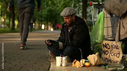 Passer giving one dollar to the homeless man in city park. photo