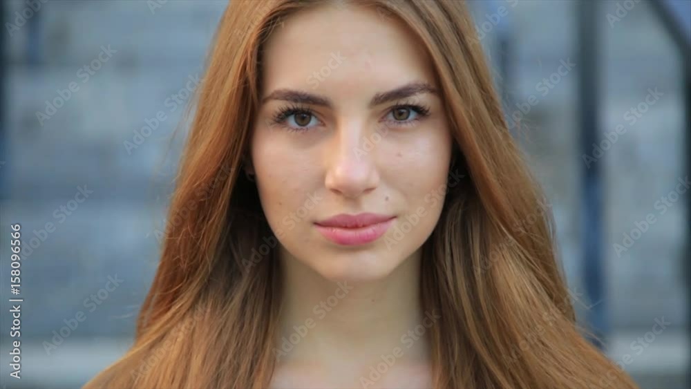Portrait of woman pretty caucasian woman with long hair smiling in the city at sunrise.