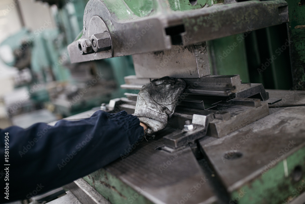 Metallurgy heavy industry. Factory for production of heavy pellet stoves and boilers. Worker hands close up. Extremely dark conditions and visible noise. Focus on foreground.