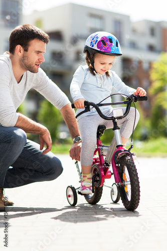 Girl learning to ride a bicycle with father
 photo