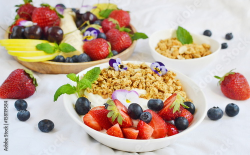 Yogurt with granola and fruits, blueberries, strawberries, cherry, apple, banana, healthy breakfast