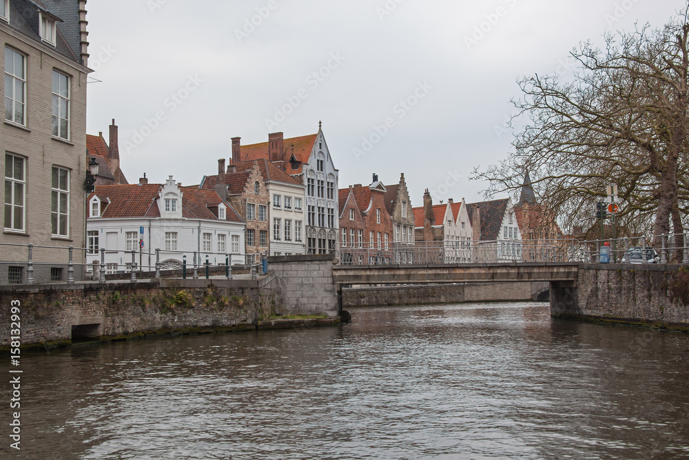 Historic medieval buildings along canal in the  tourist center of Bruges (Brugge) on a cloudy day, Belgium
