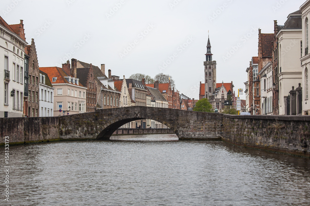 View of the bridge on canal and historic medieval architecture in the  tourist center of Bruges (Brugge) on a cloudy day, Belgium