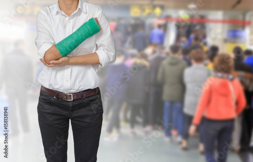 Injured woman with green cast on hand and arm on motion blur in the subway station background, body injury concept