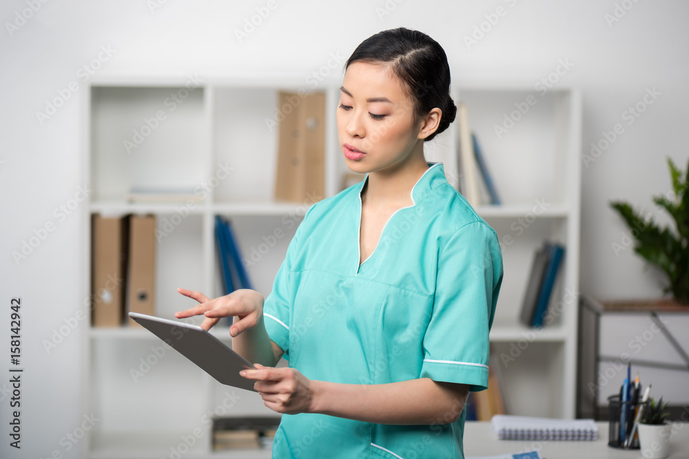 concentrated asian internist using digital tablet in professional clinic concentrated asian internist using digital tablet in professional clinic