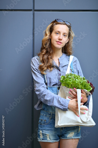 Woman with vegetables in bag on city street