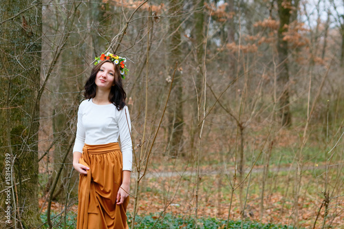 Beautiful girl with flower wreath on her head in the autumn forest
