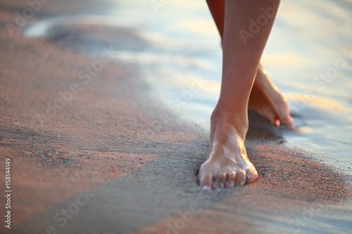 Beautiful woman legs on the beach at sunrise