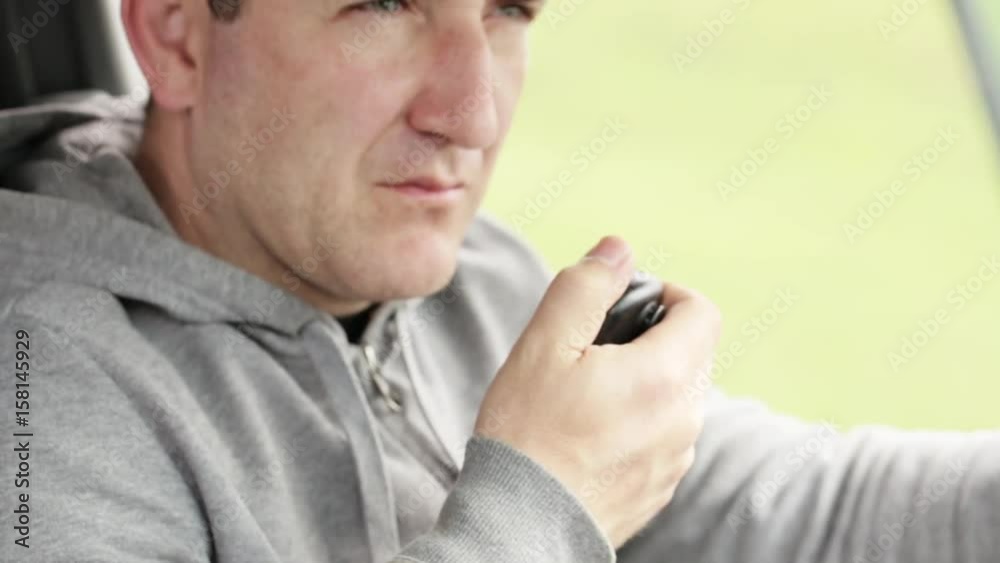 Man takinng hand microphon and talking on radio in his car.