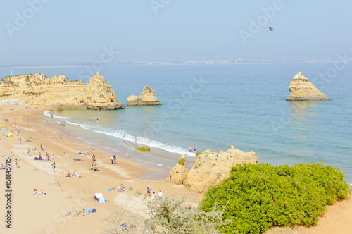 Natural beauty of the sandy beach on Algarvian coastline, Portugal. Sunny travel vacation relaxing outdoors background. Blue sky peaceful seascape view photo