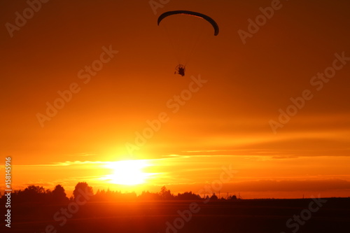Motorized paraglider on sunset background